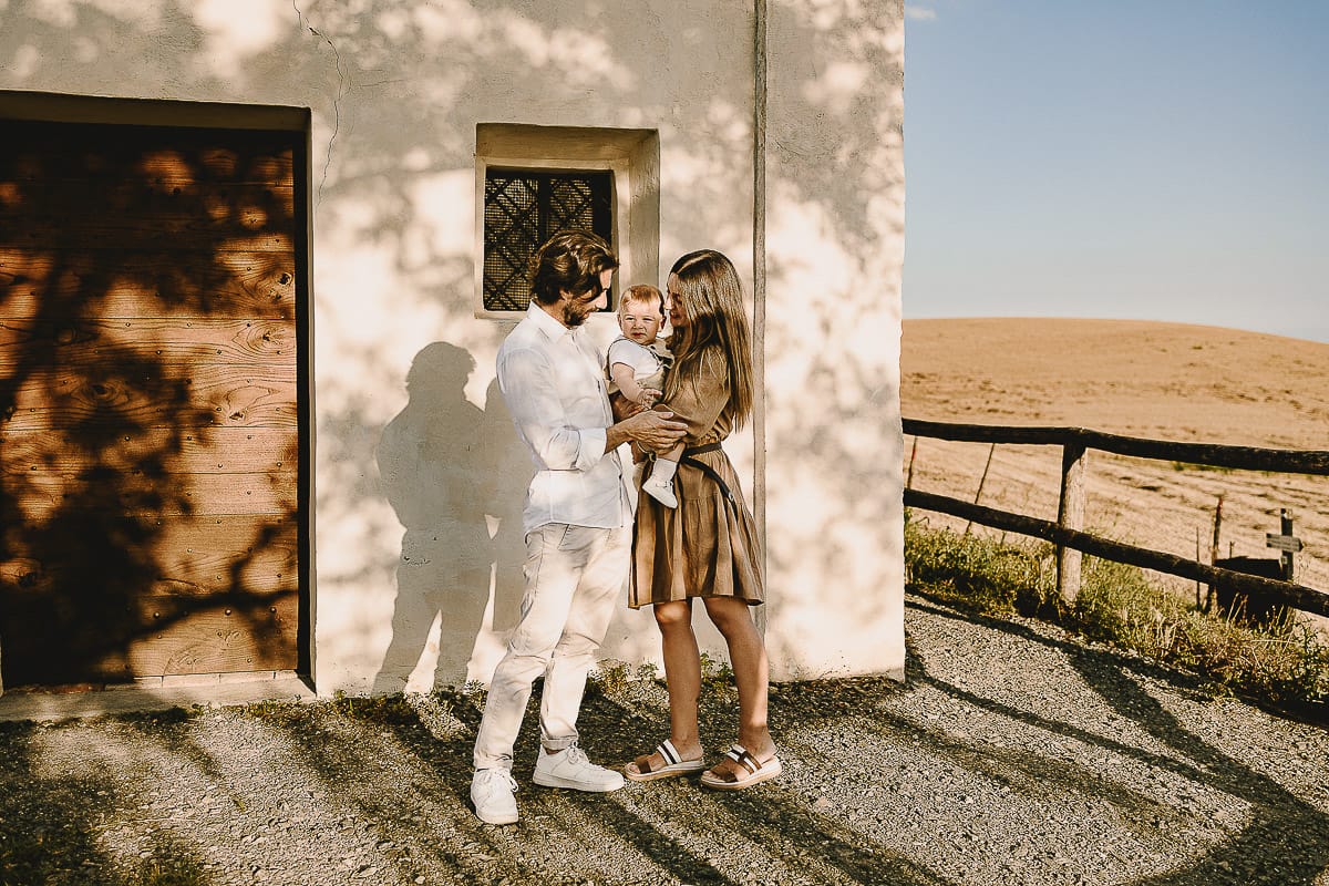 Servizio fotografico di famiglia a Torino: un tramonto dorato a Mombello di Torino. Chiara, Alessandro e il piccolo Leonardo davanti alla chiesa di San Lorenzo.