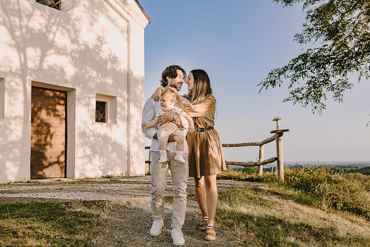 Servizio fotografico di famiglia a Torino: un tramonto dorato a Mombello di Torino. Chiara, Alessandro e il piccolo Leonardo davanti alla chiesa di San Lorenzo.