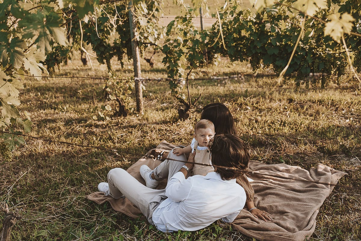 Servizio fotografico di famiglia a Torino: un tramonto dorato a Mombello di Torino. Chiara, Alessandro e il piccolo Leonardo sdraiati in un vigneto