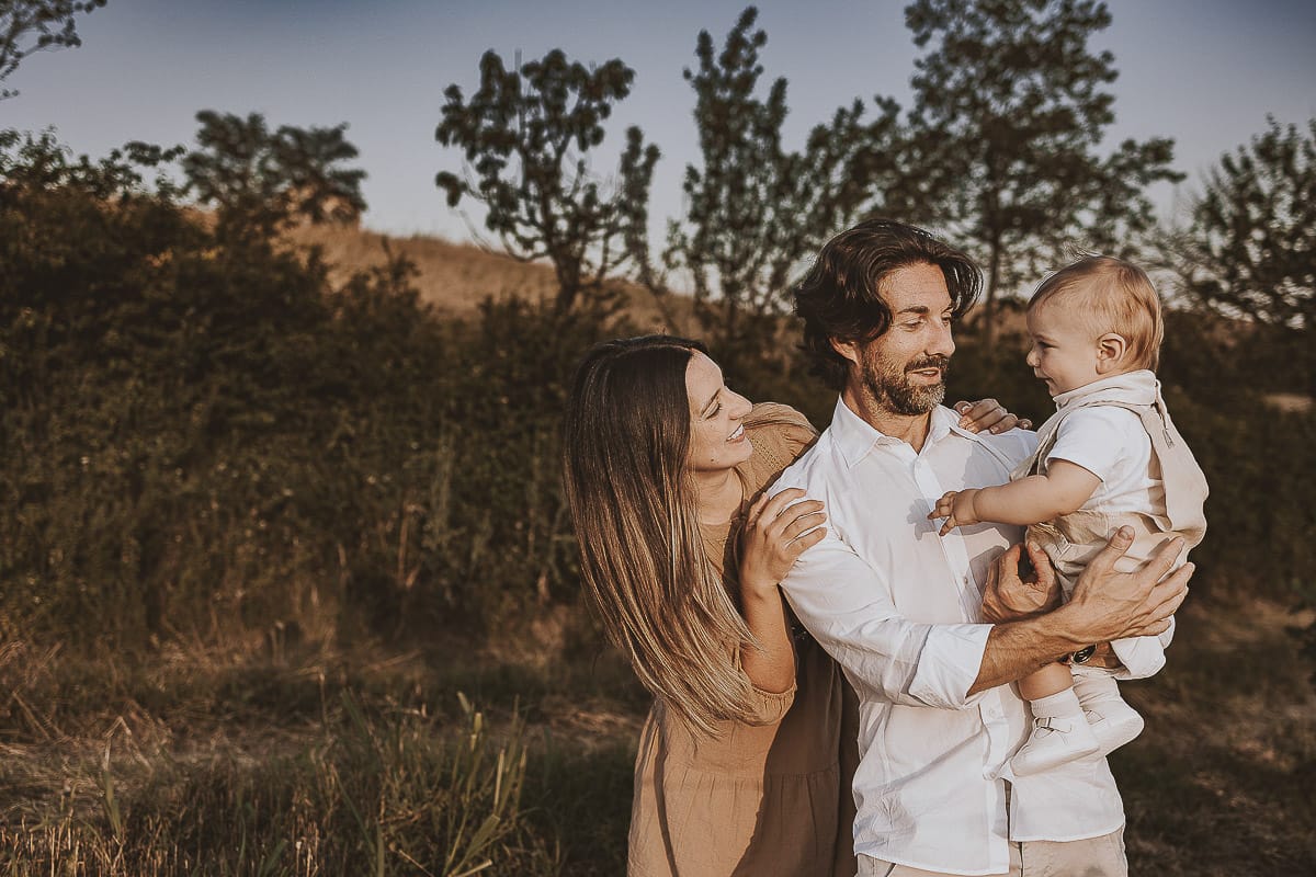 Servizio fotografico di famiglia a Torino: un tramonto dorato a Mombello di Torino. Chiara, Alessandro e il piccolo Leonardo camminano in un vigneto