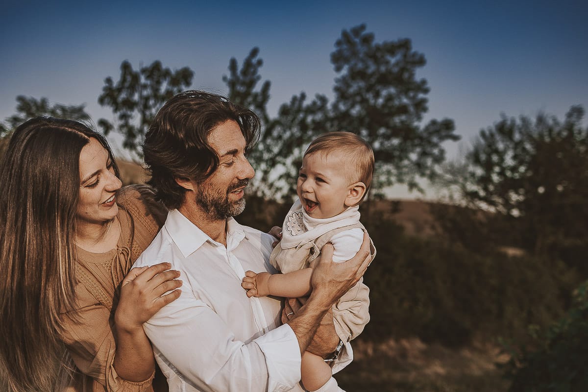 Servizio fotografico di famiglia a Torino: un tramonto dorato a Mombello di Torino. Chiara, Alessandro e il piccolo Leonardo camminano in un vigneto