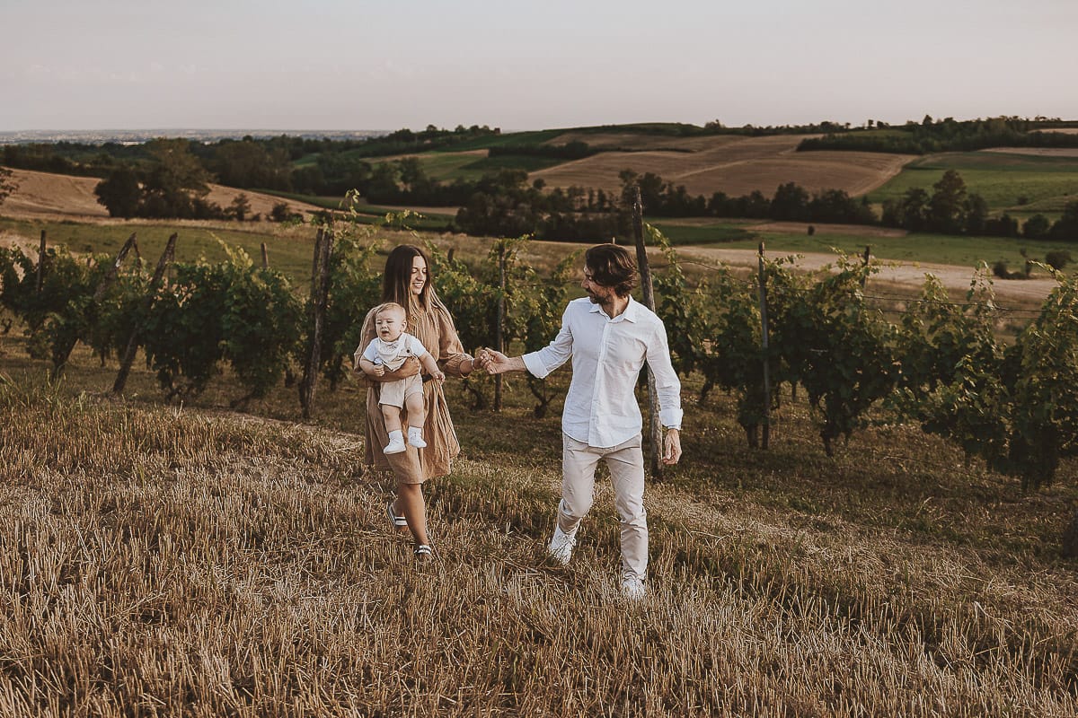 Servizio fotografico di famiglia a Torino: un tramonto dorato a Mombello di Torino. Chiara, Alessandro e il piccolo Leonardo camminano