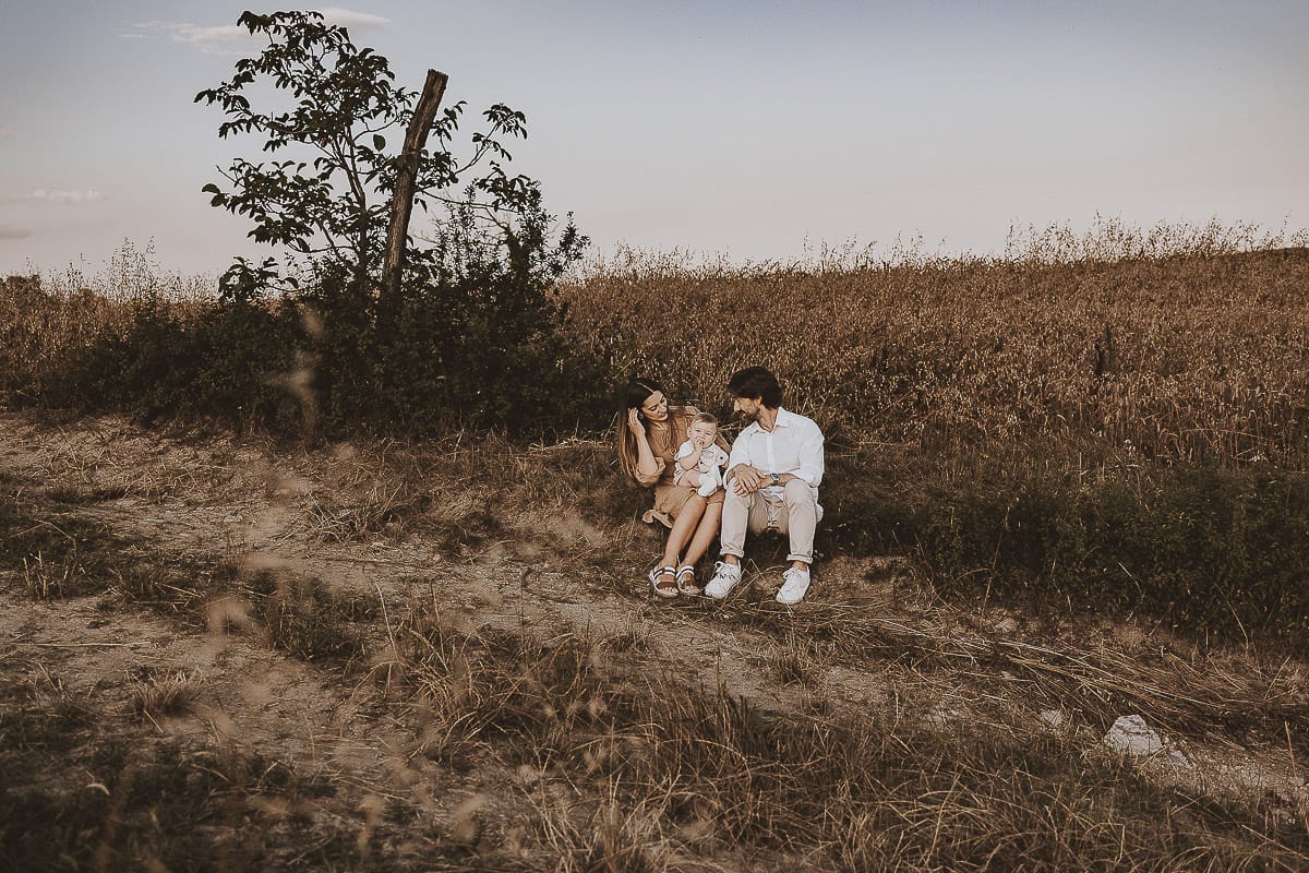 Servizio fotografico di famiglia a Torino: un tramonto dorato a Mombello di Torino. Chiara, Alessandro e il piccolo Leonardo camminano
