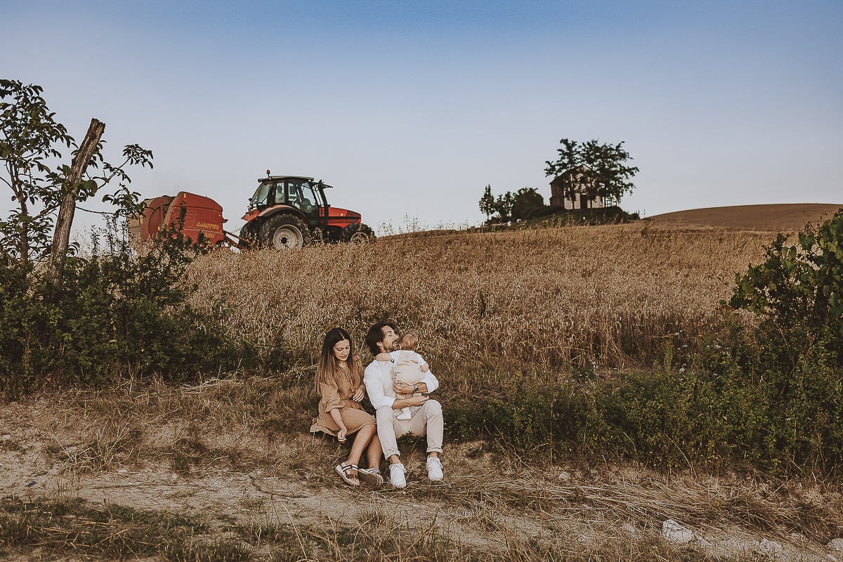 Servizio fotografico di famiglia a Torino: un tramonto dorato a Mombello di Torino. Chiara, Alessandro e il piccolo Leonardo seduti davanti ad un campo di grano