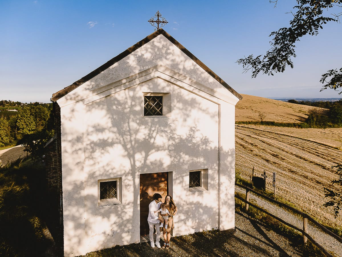 Servizio fotografico di famiglia a Torino: un tramonto dorato a Mombello di Torino. Chiara, Alessandro e il piccolo Leonardo davanti alla chiesa di San Lorenzo.