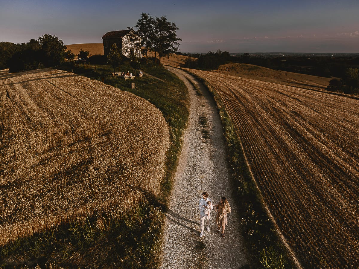 Servizio fotografico di famiglia a Torino: un tramonto dorato a Mombello di Torino. Chiara, Alessandro e il piccolo Leonardo camminano