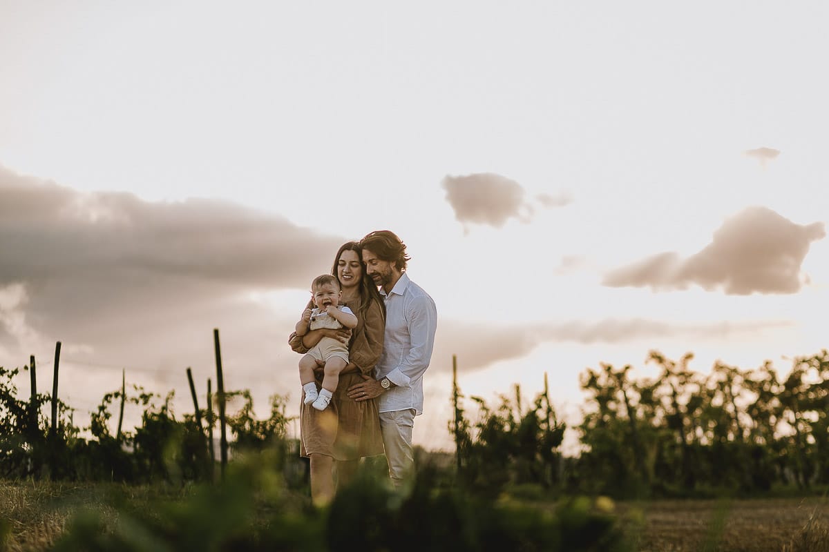 Servizio fotografico di famiglia a Torino: un tramonto dorato a Mombello di Torino. Chiara, Alessandro e il piccolo Leonardo in un campo