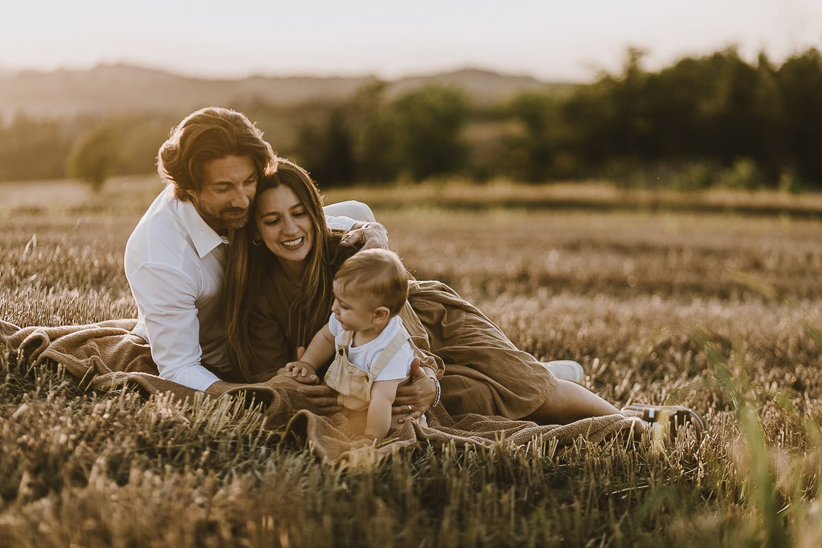 Servizio fotografico di famiglia a Torino: un tramonto dorato a Mombello di Torino. Chiara, Alessandro e il piccolo Leonardo in un campo