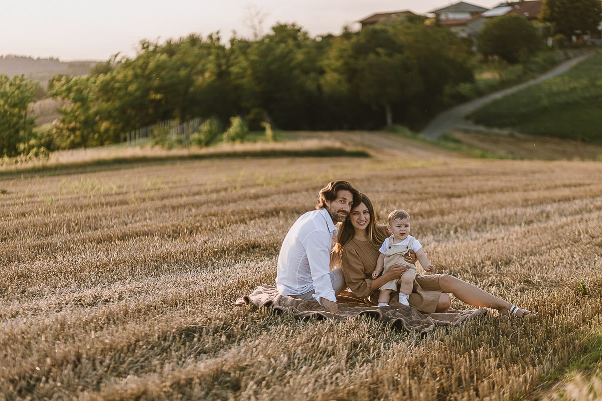 Servizio fotografico di famiglia a Torino: un tramonto dorato a Mombello di Torino. Chiara, Alessandro e il piccolo Leonardo in un campo