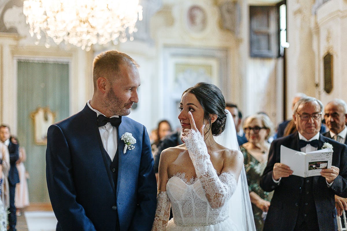 Matrimonio da favola al castello Canalis. Cerimonia. Sposa commossa si asciuga una lacrima con il dito.