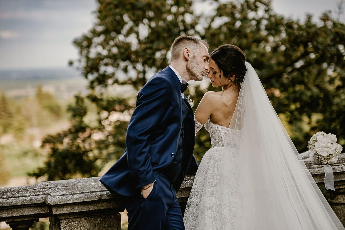 Matrimonio da favola al castello Canalis. Ritratto degli sposi. Sposi vicino alla balconata di pietra si guardano intensamente