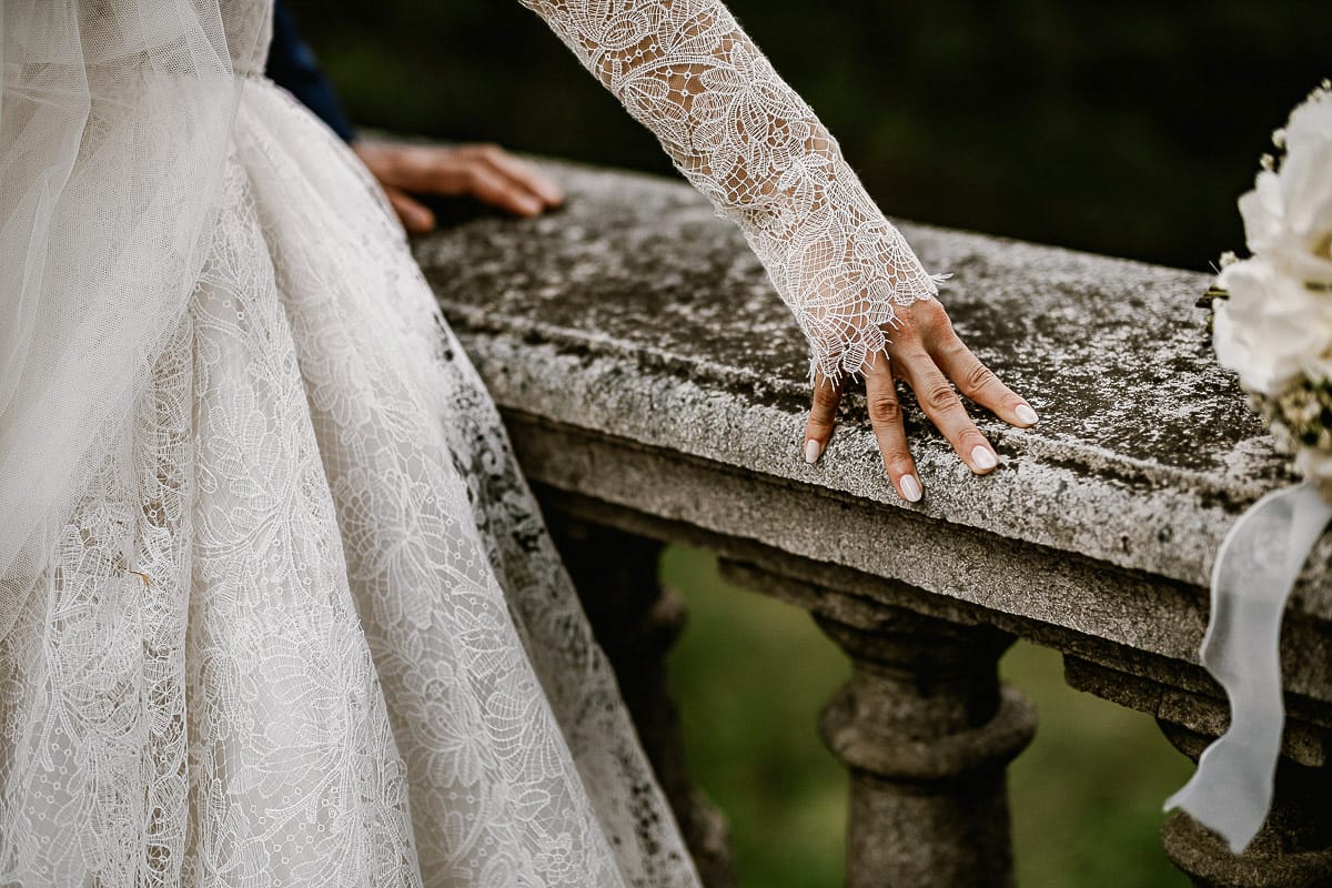Matrimonio da favola al castello Canalis. Ritratto degli sposi. Sposi vicino alla balconata di pietra dettaglio sulle mani