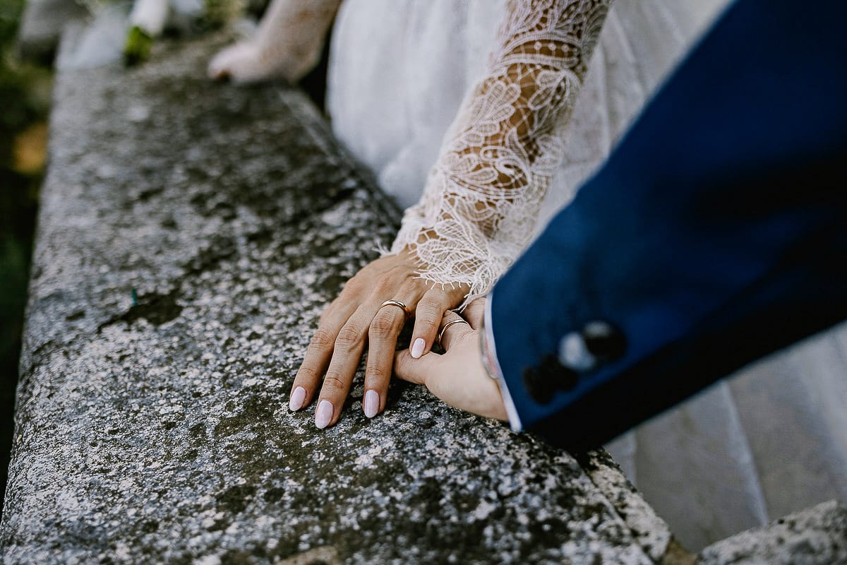 Matrimonio da favola al castello Canalis. Ritratto degli sposi. Sposi vicino alla balconata di pietra dettaglio sulle mani