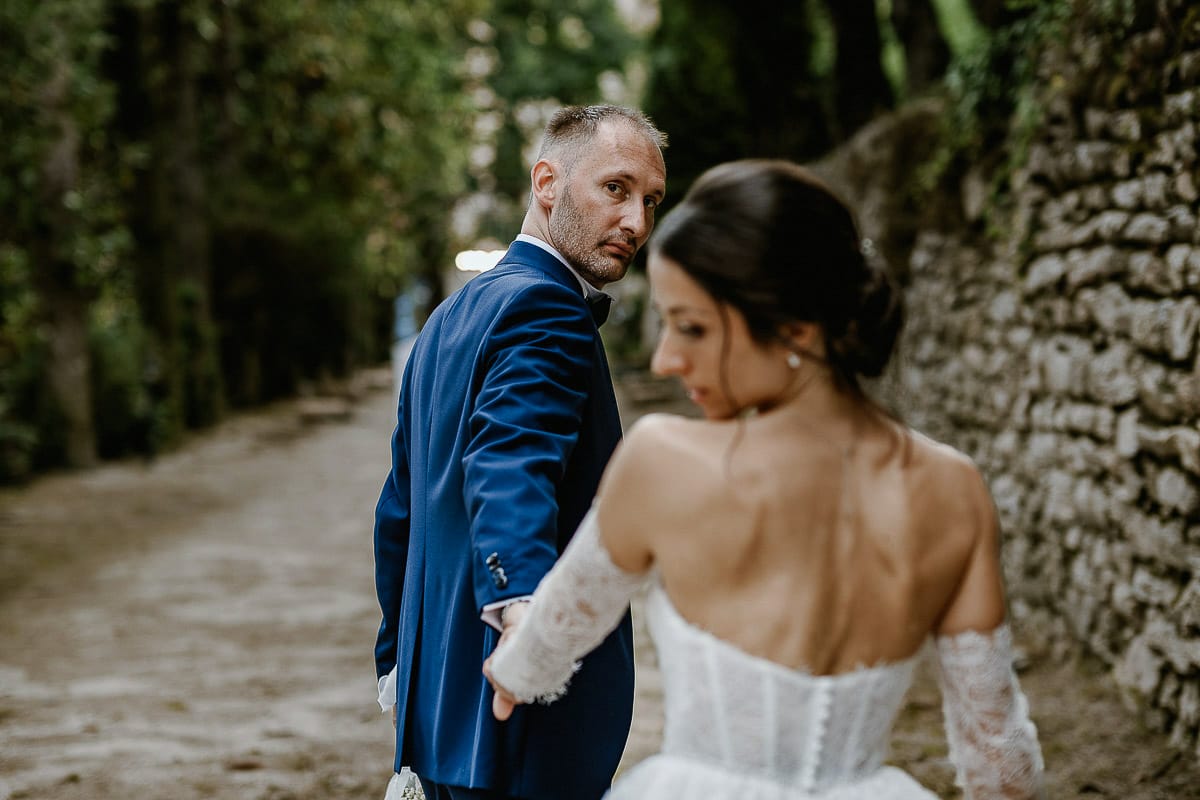 Matrimonio da favola al castello Canalis. Ritratto degli sposi nel bosco. Sposi camminano. sposo tira dolcemente la sposa.