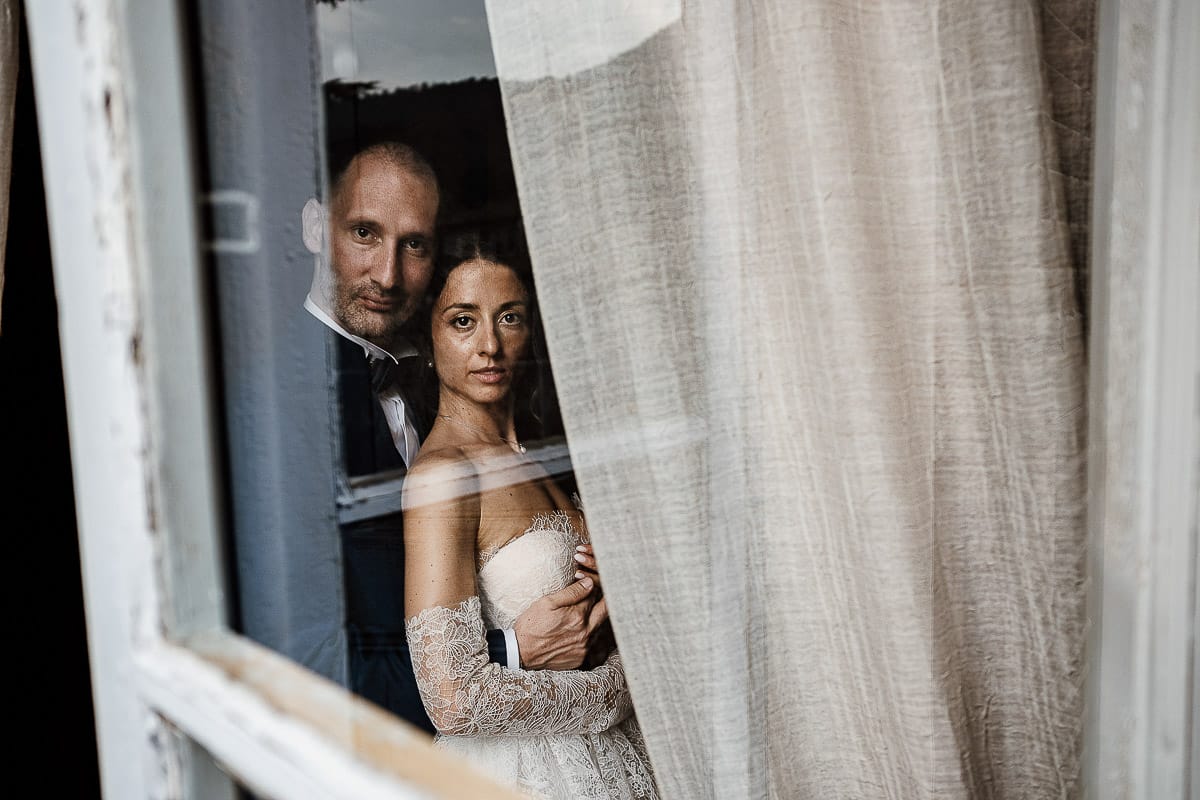 Matrimonio da favola al castello Canalis. Ritratto degli sposi nelle sale del castello. Foto attraverso il vetro di una finestra.