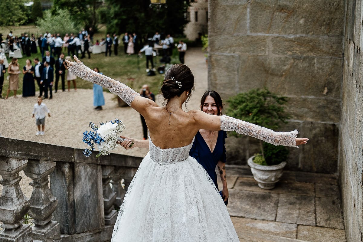 Matrimonio da favola al castello Canalis. Aperitivo. Lancio del bouquet. sposa abbraccia la ragazza che ha preso il bouquet.