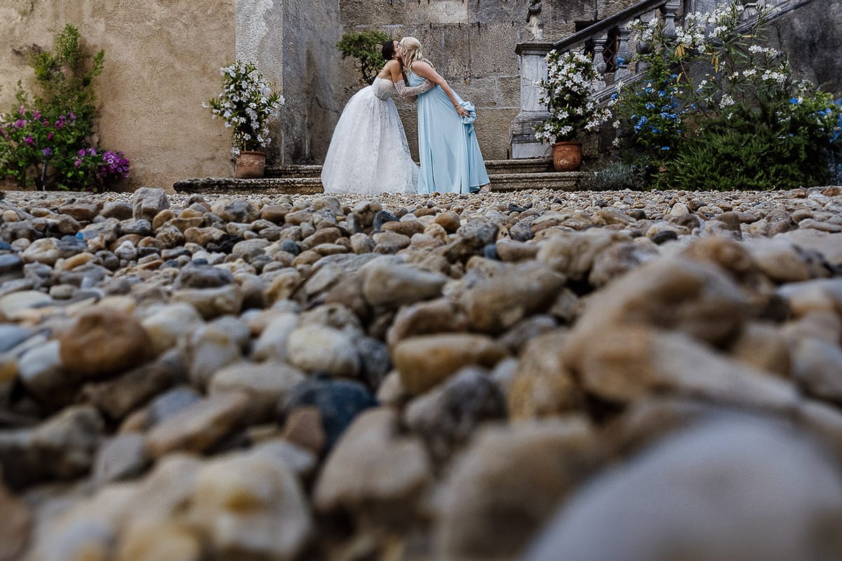 Matrimonio da favola al castello Canalis. Aperitivo. foto della sposa che bacia un'amica riprese dal drone posto sul terreno.