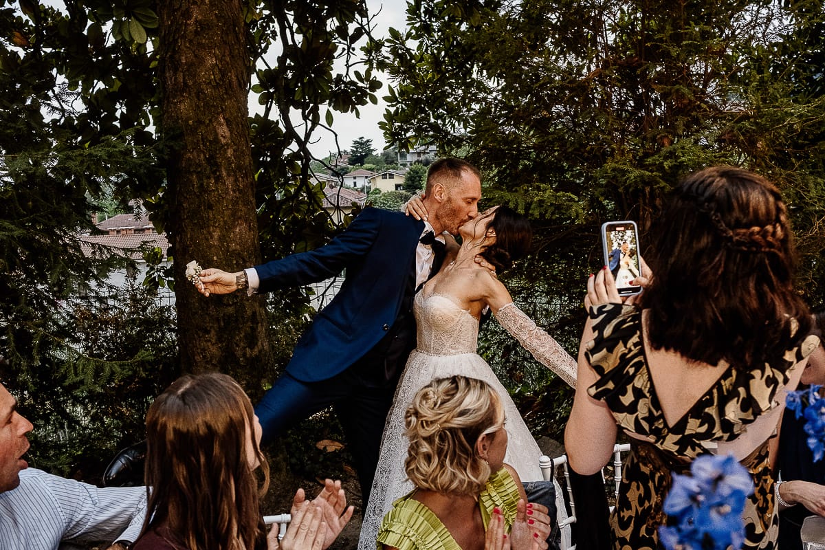 Matrimonio da favola al castello Canalis. Ricevimento. Ingresso degli sposi nel luogo della cena. Sposi si baciano, invitati applaudono e fanno fotografie con il cellulare.