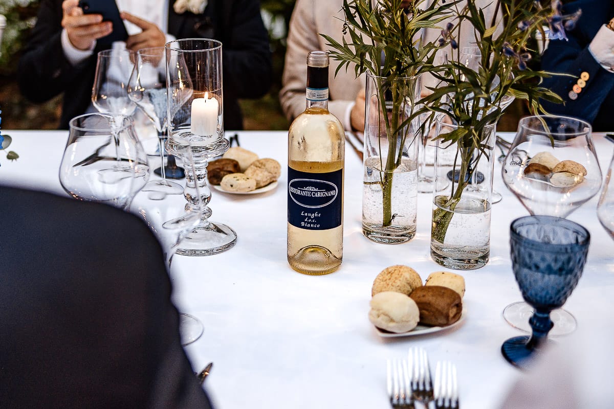 Matrimonio da favola al castello Canalis. Ricevimento. Ingresso degli sposi nel luogo della cena. tavola imbandita. bottiglia di vino bianco.