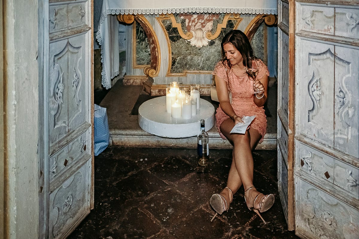 Matrimonio da favola al castello Canalis. Ricevimento. Amica seduta nella cappellina con un bicchiere e una bottiglia