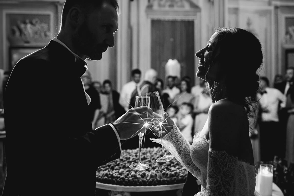 Matrimonio da favola al castello Canalis. Ricevimento. Taglio della torta. Sposi brindano. Bianco e nero.
