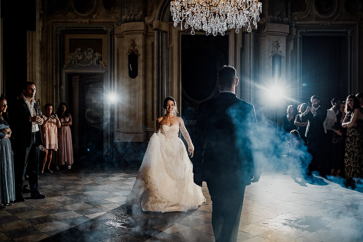 Matrimonio da favola al castello Canalis. Ricevimento. Primo ballo degli sposi nel salone delle feste affrescato. Lampadario a goccia scenografico e fumo suggestivo.