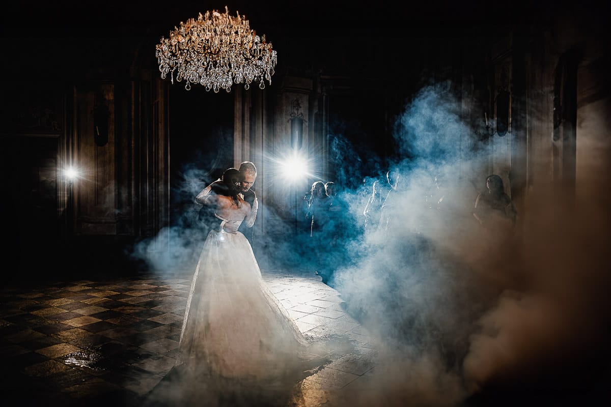 Matrimonio da favola al castello Canalis. Ricevimento. Primo ballo degli sposi nel salone delle feste affrescato. Lampadario a goccia scenografico e fumo suggestivo.