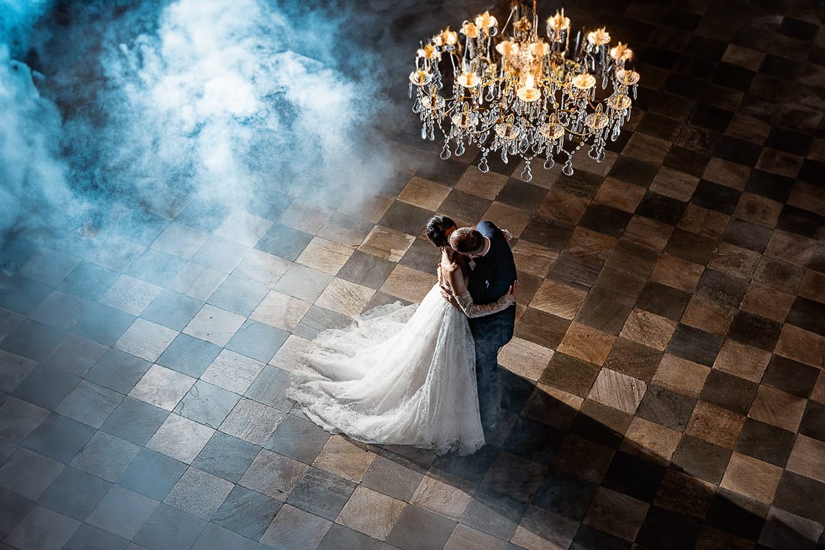 Matrimonio da favola al castello Canalis. Ricevimento. Primo ballo degli sposi nel salone delle feste affrescato. Lampadario a goccia scenografico e fumo suggestivo.