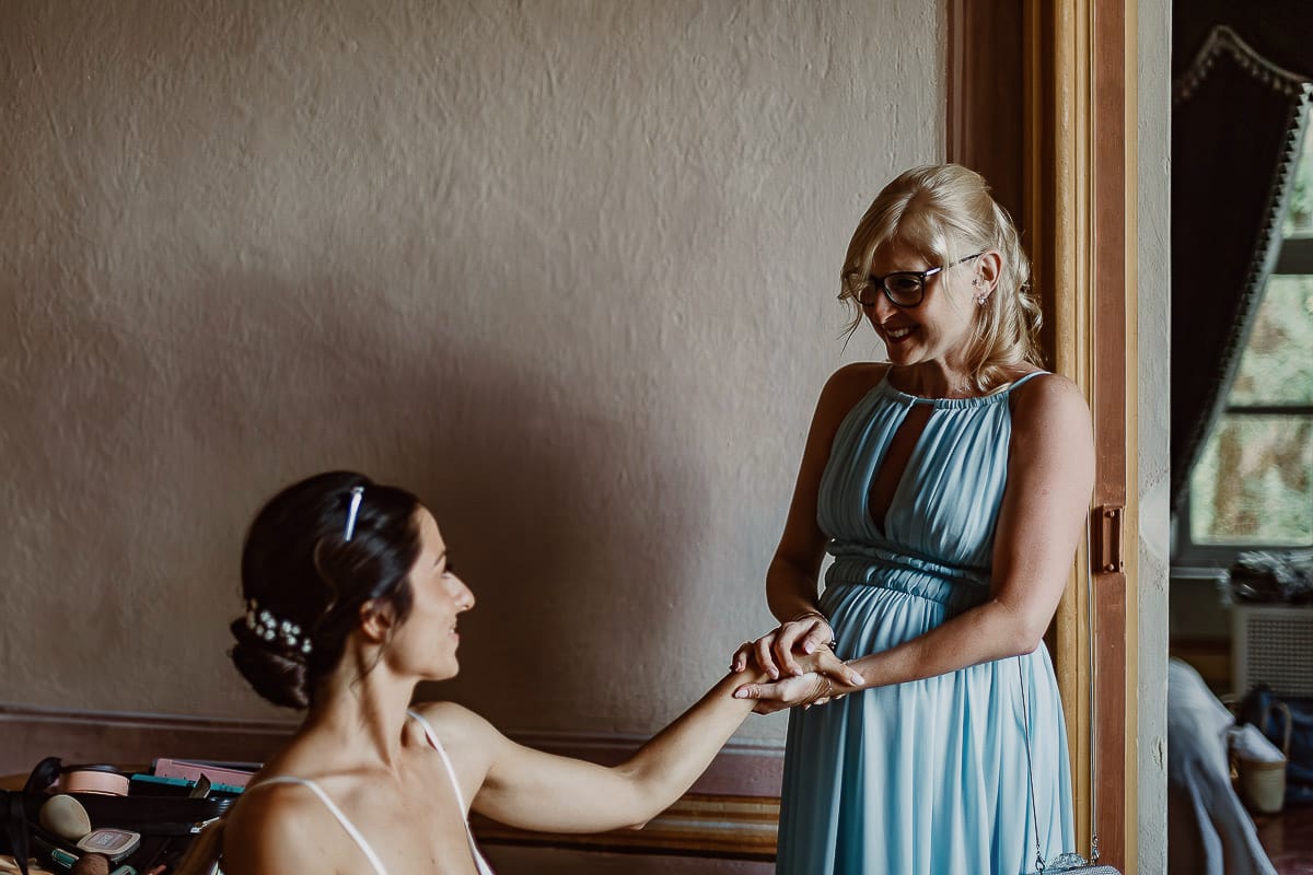 Matrimonio da favola al castello Canalis. Preparazione della sposa. Amica prende la mano della sposa.