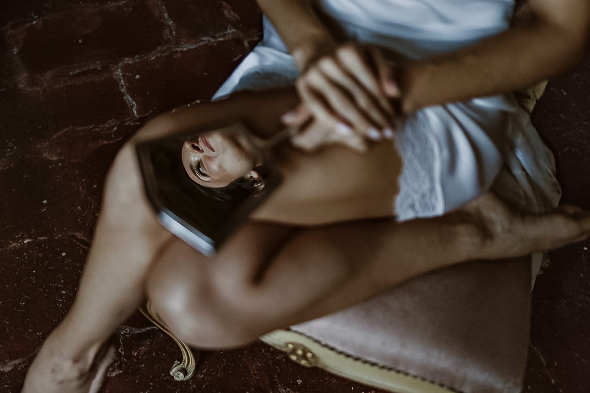 Matrimonio da favola al castello Canalis. Preparazione della sposa. Sposa riflessa in uno specchio antico tenuto in grembo
