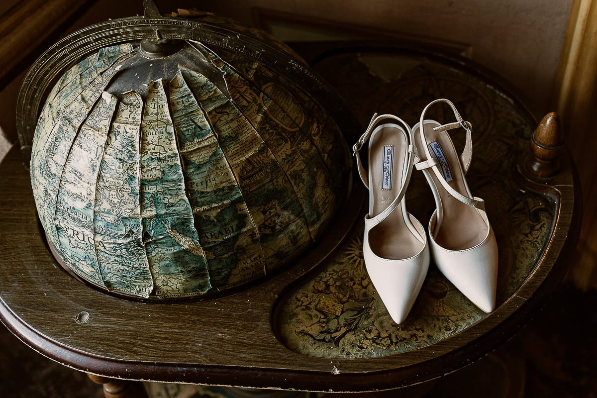 Matrimonio da favola al castello Canalis. Preparazione della sposa.Scarpe vicine al mappamondo antico