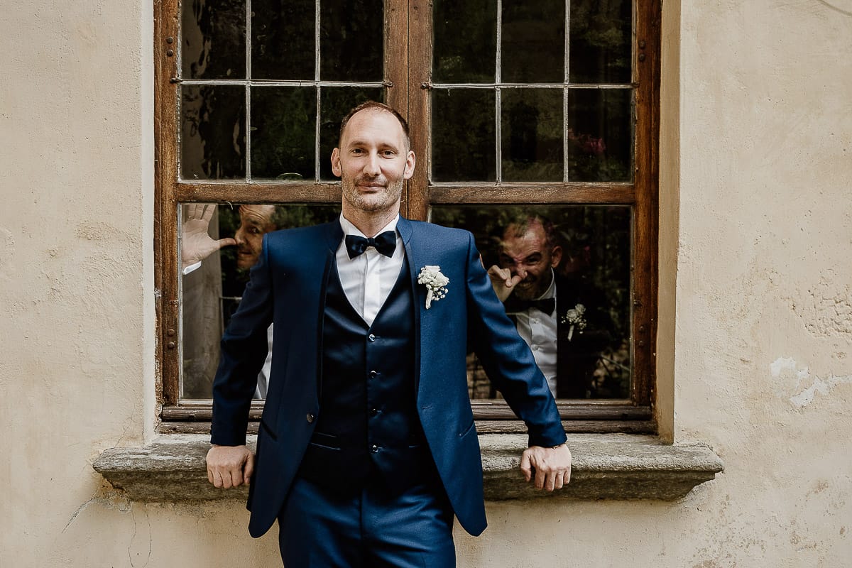 Matrimonio da favola al castello Canalis.Ritratto dello sposo.Gli amici fanno delle smorfie alla finestra dietro di lui.