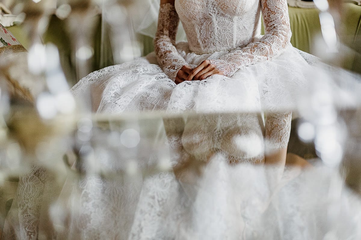 Matrimonio da favola al castello Canalis. Preparazione della sposa.Dettaglio della sposa seduta sul divano riflessa nel tavolino di vetro.