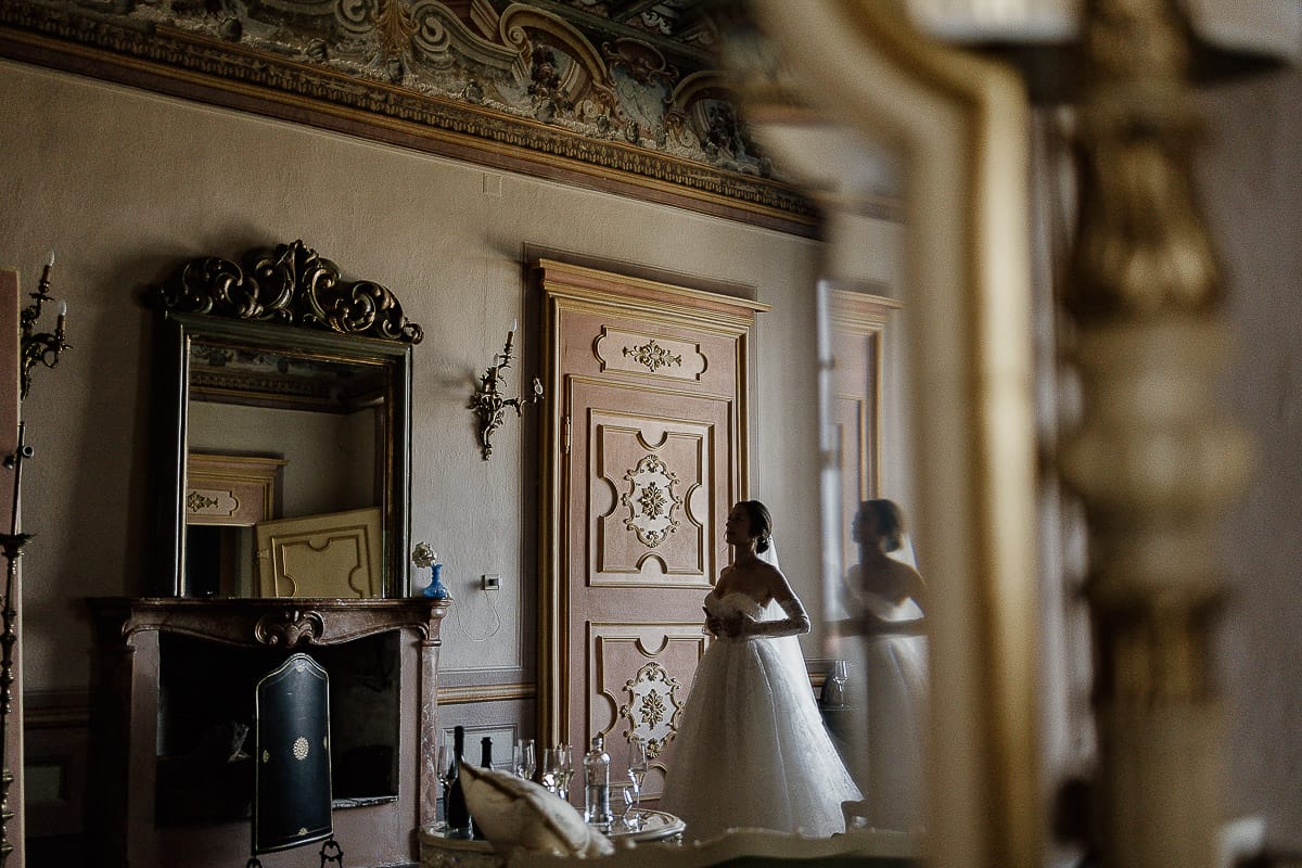 Matrimonio da favola al castello Canalis. Preparazione della sposa.Ritratto della sposa e della stanza ripresa da una specchiera.