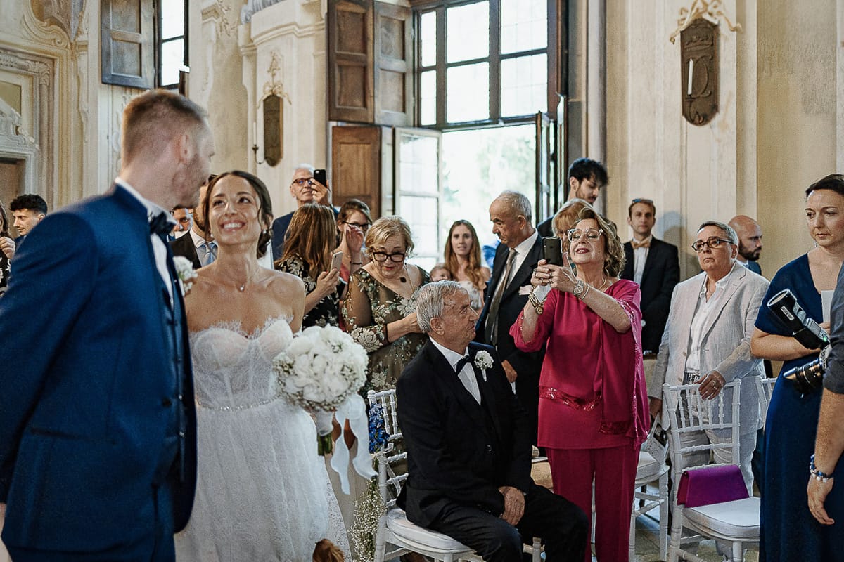 Matrimonio da favola al castello Canalis. Cerimonia. mamma della sposa fa le foto con il cellulare.
