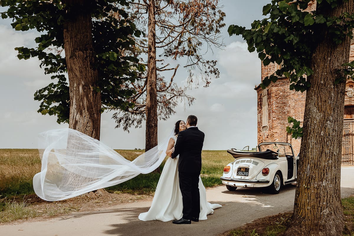 Matrimonio a Riva presso Chieri. Ritratti degli sposi. Sposi davanti all'auto, un maggiolino bianco d'epoca decappottabile