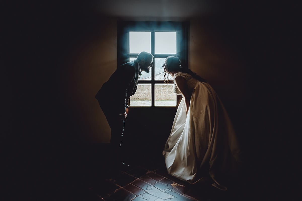 Matrimonio al Castello di Cortanze. Ritratto degli sposi davanti ad una finestra in controluce.