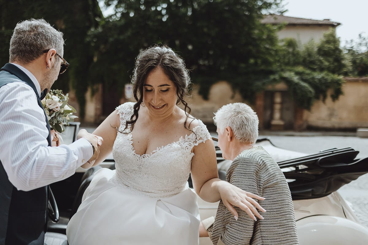 Matrimonio a Riva presso Chieri. Cerimonia. Sposa esce dall'auto. la madre le sistema il velo