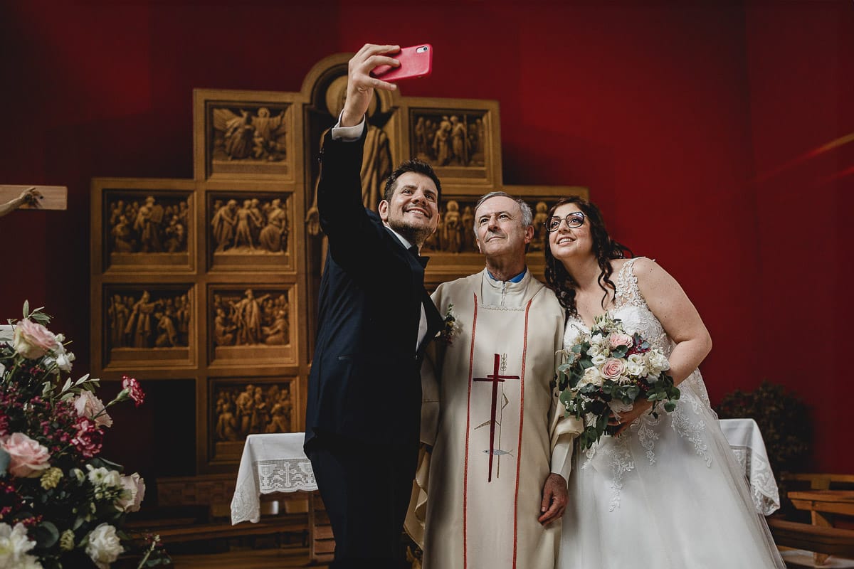 Matrimonio a San Mauro Torinese. Cerimonia. Selfie degli sposi con il sacerdote.