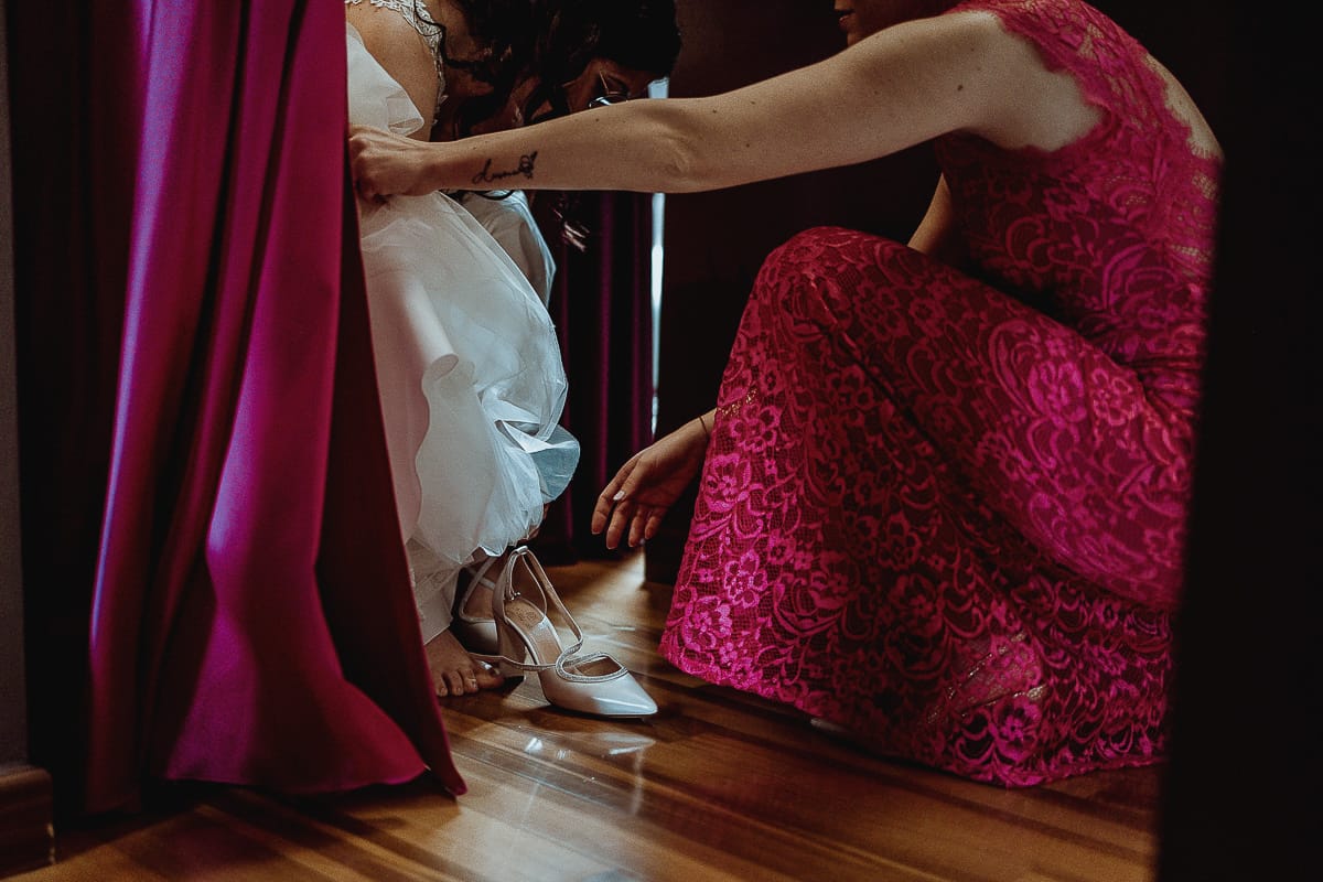 Matrimonio a San Mauro Torinese. Preparazione della sposa. Vestizione della sposa. La testimone mette le scarpe alla sposa