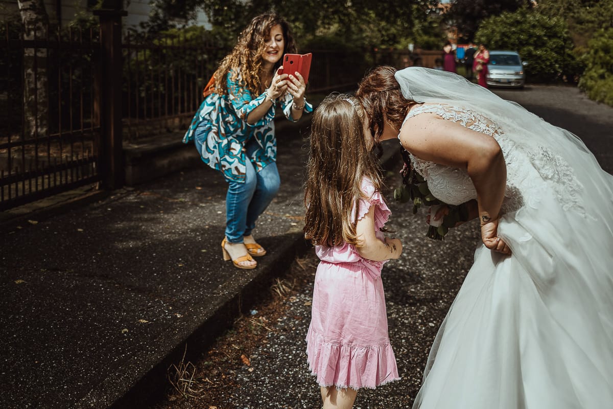 Matrimonio a San Mauro Torinese. Preparazione della sposa. Vestizione della sposa. Vicina di casa fotografa la sposa con la sua bambina