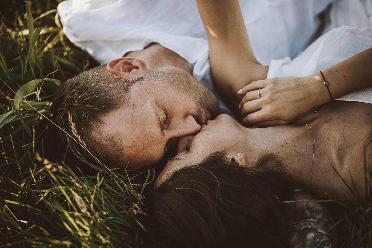 Prewedding romantico e da sogno al tramonto in Monferrato. Valeria e Omar sdraiati fra l'erba si baciano.
