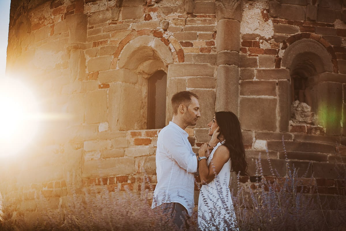Prewedding romantico e da sogno in Monferrato. Valeria e Omar in mezzo ai fiori dietro la chiesa romanica di San Lorenzo. Il sole del tramonto crea un flare