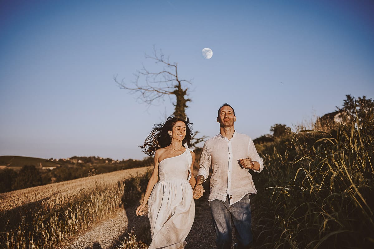 Prewedding romantico e da sogno al tramonto in Monferrato. Valeria e Omar corrono. Dietro di loro la luna piena