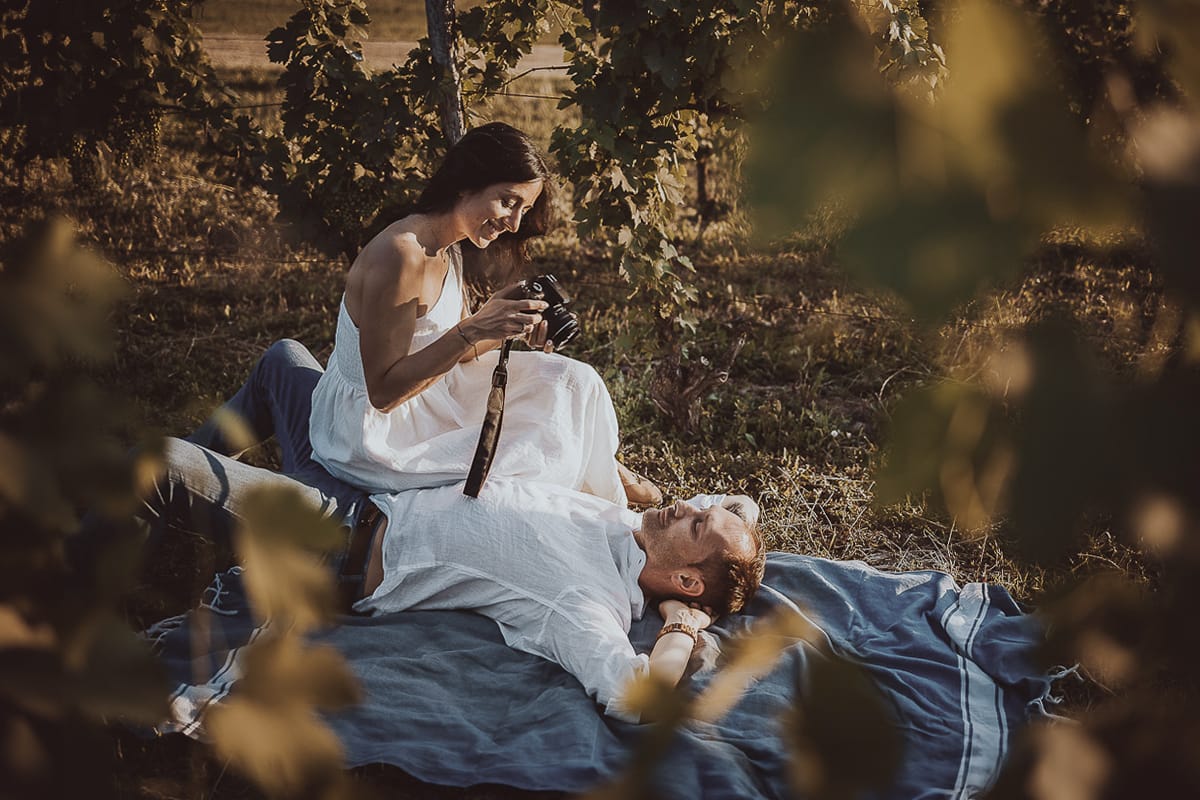 Prewedding romantico e da sogno al tramonto in Monferrato. Omar sdraiato nel vigneto. Valeria si appresta a fotografarlo