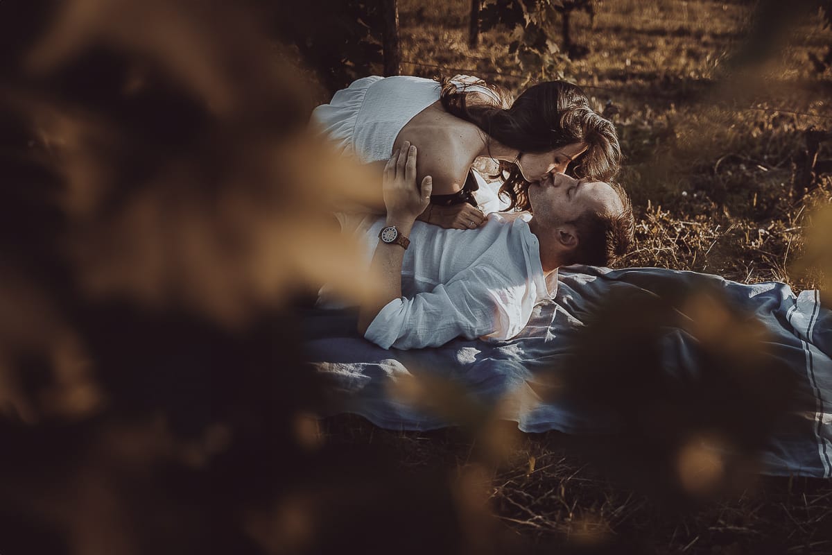 Prewedding romantico e da sogno al tramonto in Monferrato. Omar sdraiato nel vigneto. Valeria lo bacia