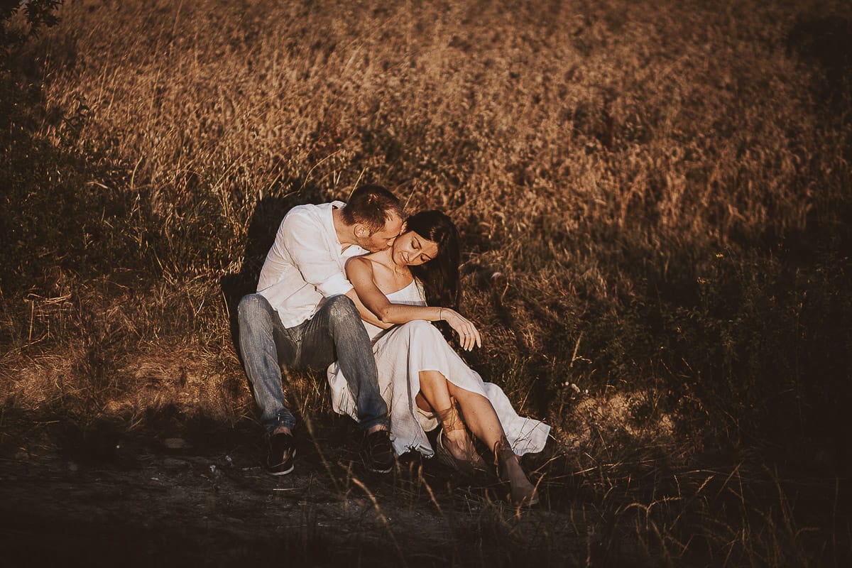 Prewedding romantico e da sogno al tramonto in Monferrato. Valeria e Omar seduti al bordo di un campo di grano.