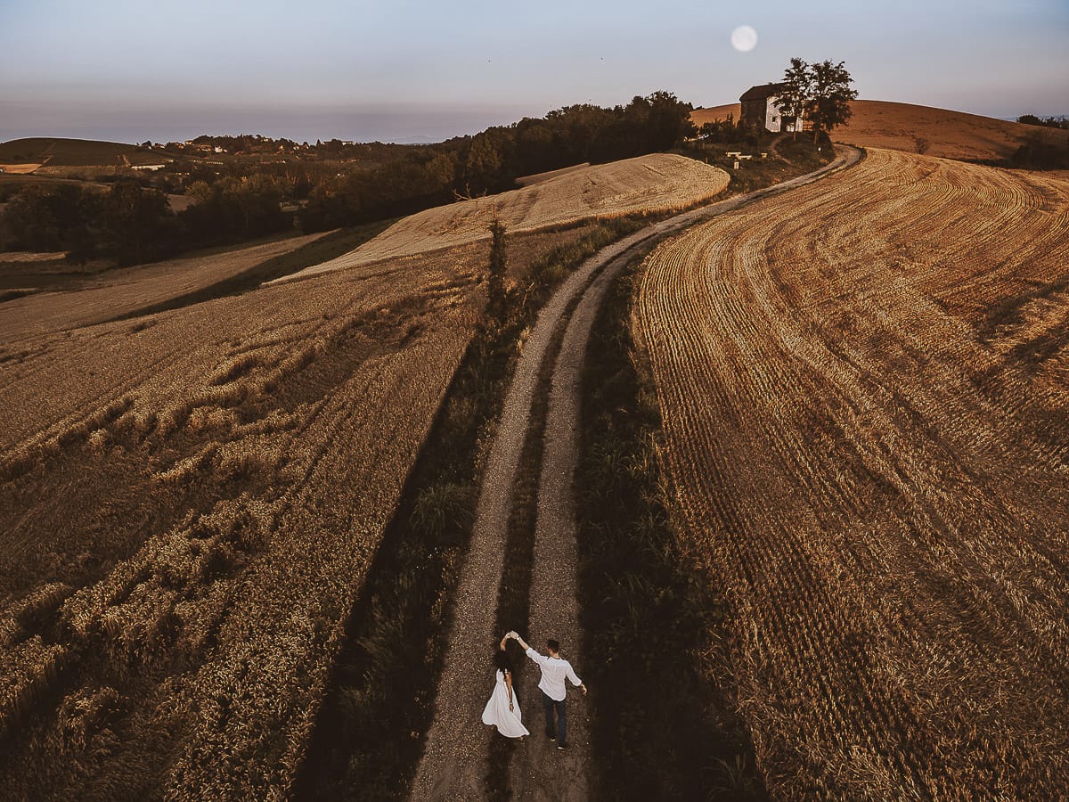Prewedding romantico e da sogno al tramonto in Monferrato. Omar fa fare una piroetta a Valeria. Foto ripresa dal drone con il panorama e la luna piena.