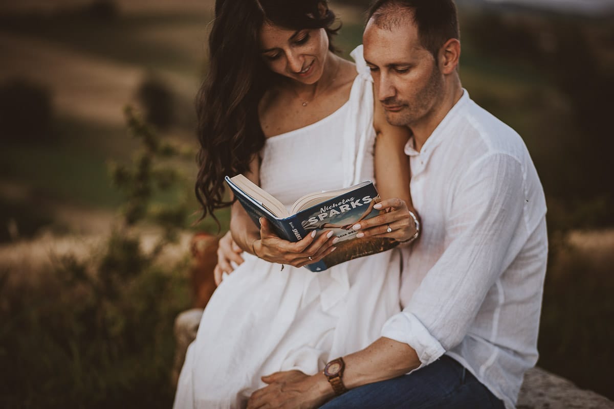 Prewedding romantico e da sogno al tramonto in Monferrato. Valeria e Omar sono seduti su di una panchina e leggono un libro.