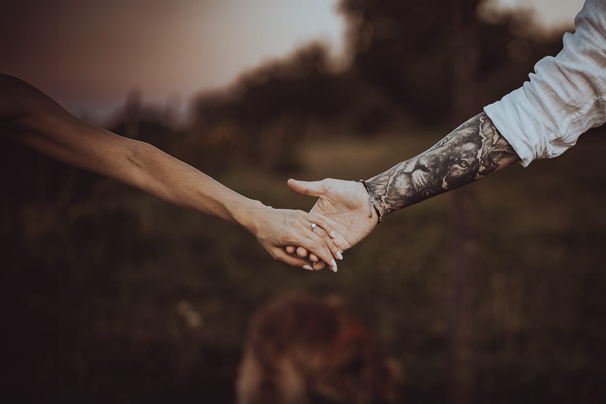 Prewedding romantico e da sogno al tramonto in Monferrato. Valeria e Omar si danno la mano. Particolare del tatuaggio sul braccio di Omar che raffigura un leone..